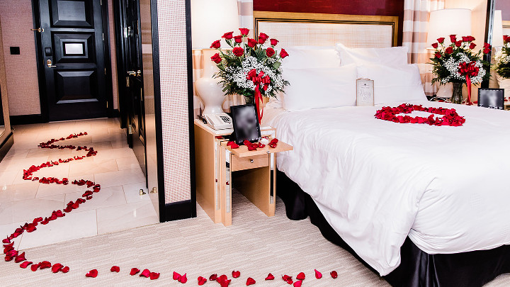 Romantic Vegas proposal in hotel room with roses leading to bed