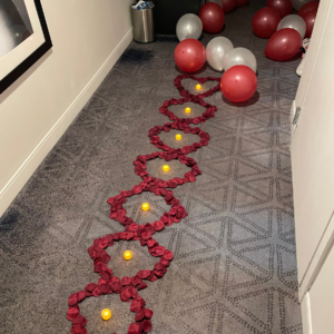 Rose petals, candles and balloons arranged in a Vegas hotel room as decor for a marriage proposal