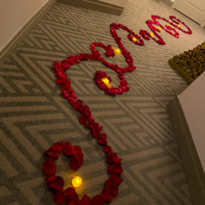 Rose petals and candles arranged on floor for hotel room decoration marriage proposal