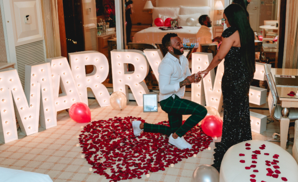 A couple celebrates their marriage proposal in a Las Vegas hotel room with decorations including rose petals, balloons and MARRY ME letters