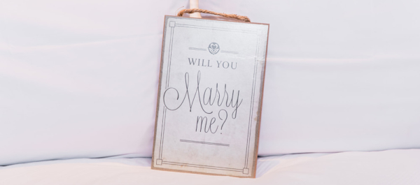 "Will You Marry Me?" wooden sign on bed for marriage proposal