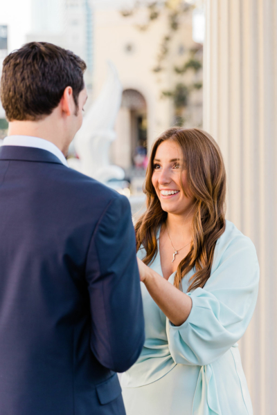 A woman looks at a man and smiles before their marriage proposal in Las Vegas, as a photographer takes their picture