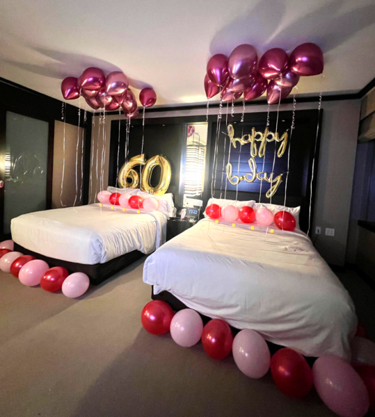Las Vegas hotel room decorated for a birthday, with balloons and "happy birthday" banner on 2 beds